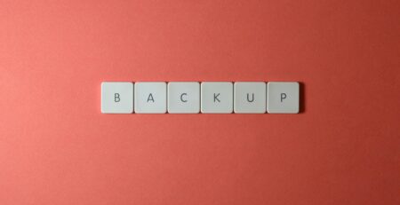 Free Close-up of keyboard keys spelling 'BACKUP' placed on a coral-colored surface. Stock Photo